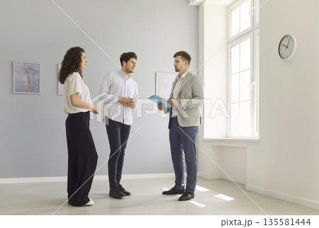 Couple of clients and real estate agent meeting for empty home apartment tour Couple of clients and real estate agent meeting for empty home apartment tour 135581444