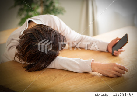 部屋でスマホを見てだらけるミドル女性 部屋でスマホを見てだらけるミドル女性 135581467