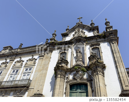 Facade of a historic baroque church with ornate stone carvings, decorative windows, and a central Facade of a historic baroque church with ornate stone carvings, decorative windows, and a central 135582454