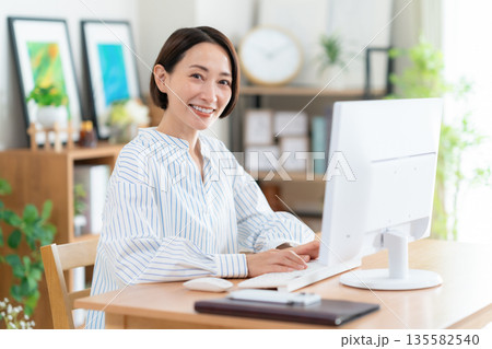リビングでテレワークをするミドルの女性 リビングでテレワークをするミドルの女性 135582540