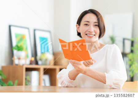 リビングで年金手帳を見るミドルの女性 135582607