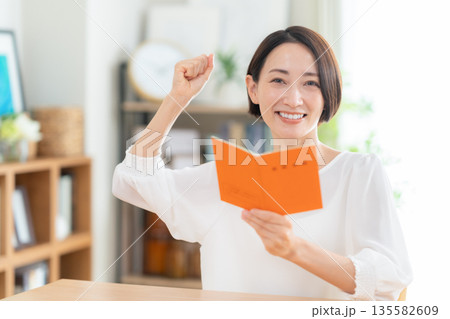 リビングで年金手帳を見るミドルの女性 135582609