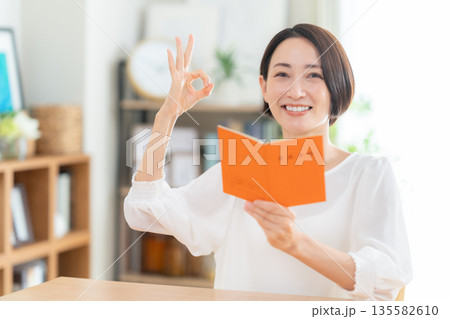 リビングで年金手帳を見るミドルの女性 135582610