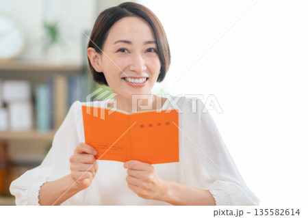 リビングで年金手帳を見るミドルの女性 135582614