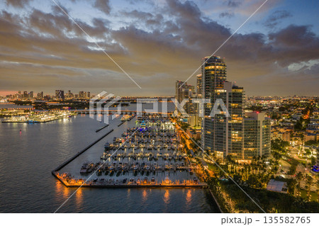 Twilight over Miami skyline and marina. Luxury yachts glowing in the Miami harbor. Sunset cruise near Miami downtown skyscrapers. Aerial night view of Miami Beach at dusk. Twilight over Miami skyline and marina. Luxury yachts glowing in the Miami harbor. Sunset cruise near Miami downtown skyscrapers. Aerial night view of Miami Beach at dusk. 135582765