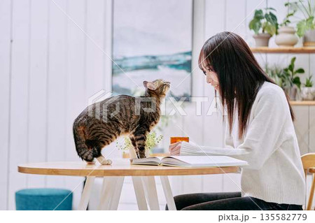 リビングのテーブルで猫とくつろぐ若い女性 135582779