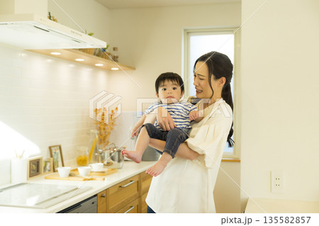 キッチンで赤ちゃんを抱っこするママ キッチンで赤ちゃんを抱っこするママ 135582857