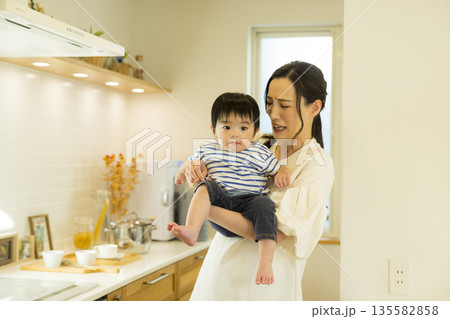 キッチンで赤ちゃんを抱っこするママ キッチンで赤ちゃんを抱っこするママ 135582858