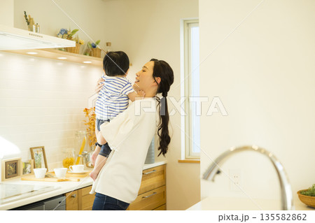 キッチンで赤ちゃんを抱っこするママ 135582862