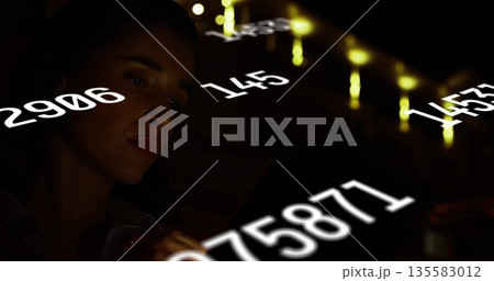 Analyzing woman in button-up shirt interpreting white numeric data in dark control room, copy space 135583012