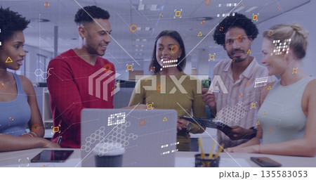 Reviewing team members collaborating around laptop in open office with floating digital graphics 135583053