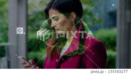 Gazing woman wearing magenta coat checking smartphone at glass bus stop, with data visualization Gazing woman wearing magenta coat checking smartphone at glass bus stop, with data visualization 135583277