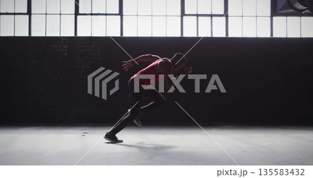 Launching male athlete sprinting across warehouse floor, with red sports top, black tights Launching male athlete sprinting across warehouse floor, with red sports top, black tights 135583432
