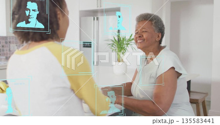 Interacting grandmother and granddaughter exploring face overlays at kitchen counter with plant 135583441