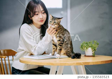 テーブルの上で猫を撫でて愛でる女性 テーブルの上で猫を撫でて愛でる女性 135583523