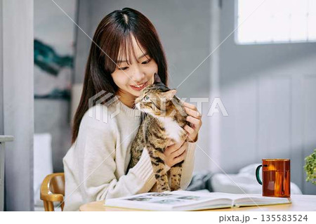 テーブルの上で猫を撫でて愛でる女性 テーブルの上で猫を撫でて愛でる女性 135583524