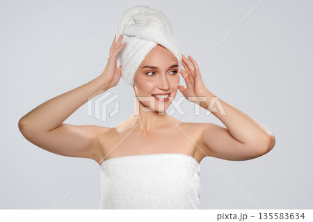 Woman in a towel posing with a towel wrapped around her hair in a clean space Woman in a towel posing with a towel wrapped around her hair in a clean space 135583634