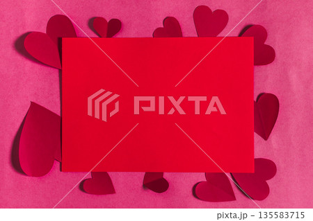 Colorful paper hearts surround a blank red card on a pink background during celebration 135583715
