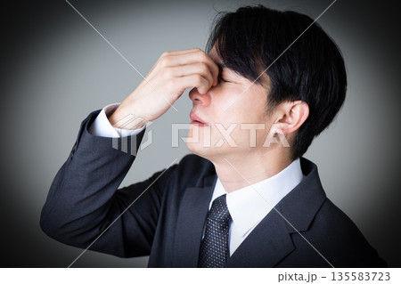 目頭を押さえて苦しむスーツのミドル男性 135583723