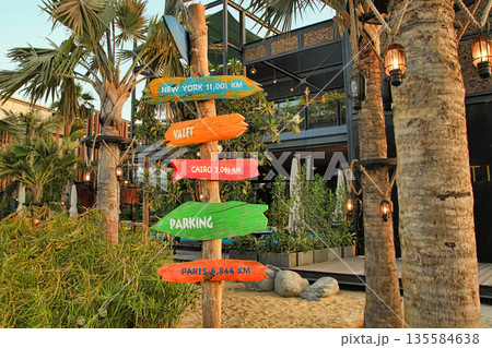 La Mer in Dubai, UAE - May 06, 2018: Signpost on the beach of La Mer at sunset. It is a new beachfront district with shopping and restaurants in Jumeirah. DUBAI, UAE -May 06, 2018 . La Mer in Dubai, UAE - May 06, 2018: Signpost on the beach of La Mer at sunset. It is a new beachfront district with shopping and restaurants in Jumeirah. DUBAI, UAE -May 06, 2018 . 135584638