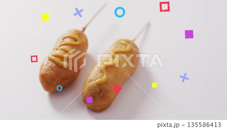 Featuring two battered corn dogs resting on white table, with mustard drizzles and geometric shapes Featuring two battered corn dogs resting on white table, with mustard drizzles and geometric shapes 135586413