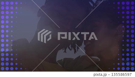 Leaning heads together couple wearing light jacket and t-shirt under clear sky, purple dot overlay 135586597