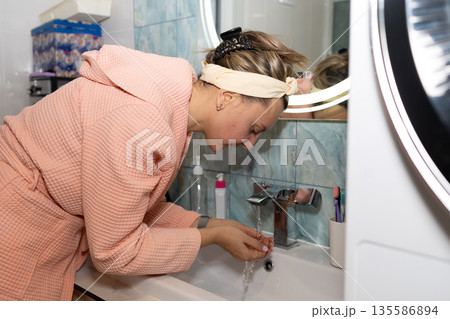 Woman Washing Hands at Sink in Bathroom During Morning Routine Woman Washing Hands at Sink in Bathroom During Morning Routine 135586894
