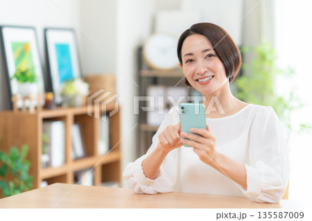 リビングでスマホを見るミドルの女性 リビングでスマホを見るミドルの女性 135587009