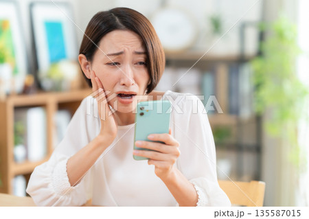 リビングでスマホを見るミドルの女性 135587015