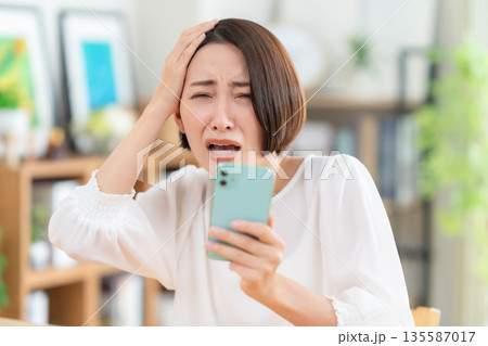 リビングでスマホを見るミドルの女性 135587017