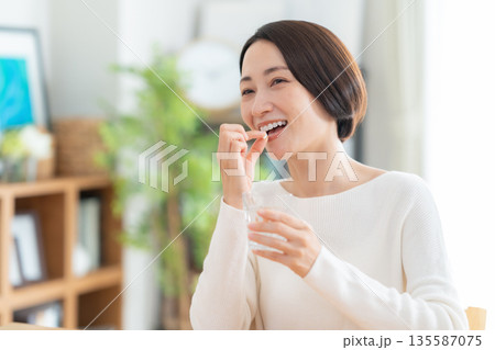 家でサプリメントを飲むミドルの女性 135587075