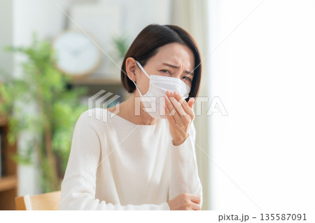 リビングでマスクをかけるミドルの女性 リビングでマスクをかけるミドルの女性 135587091