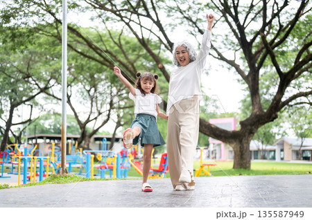 Old woman grandmother holding hand and funny walking with a kid girl granddaughter in park or garden Old woman grandmother holding hand and funny walking with a kid girl granddaughter in park or garden 135587949
