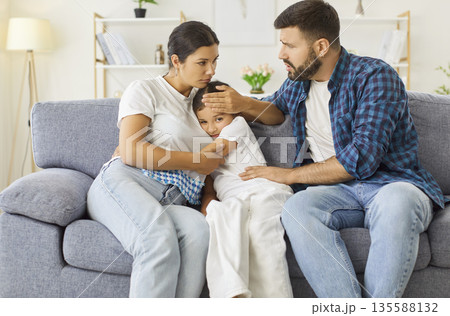 Worried parents comforting sad child on couch during family crisis at home 135588132
