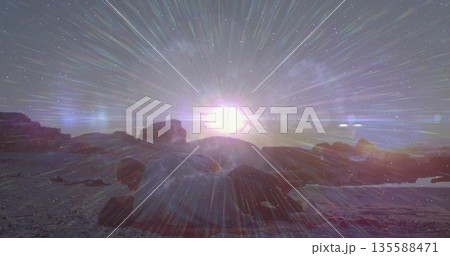 Shining bright sun emitting radial light across rocky shore, with boulders and shallow water pools 135588471