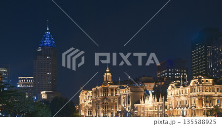 Shanghai skyline at twilight showcasing historic colonial Custom House with golden dome and modern glass skyscrapers, blending heritage and contemporary architecture against evening sky 135588925