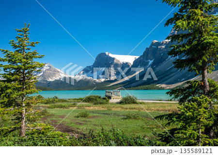山を背景にしたボウ湖の湖畔遊歩道の木製歩道橋。アルバータ州、カナダ 135589121
