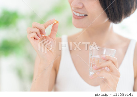 家でサプリメントを飲むミドルの女性 135589143