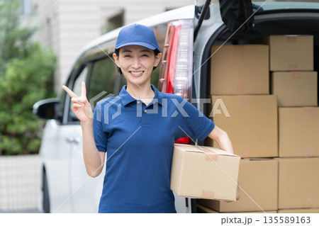 車で荷物を配達するミドルの女性配達員 135589163