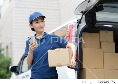 車で荷物を配達するミドルの女性配達員 135589173