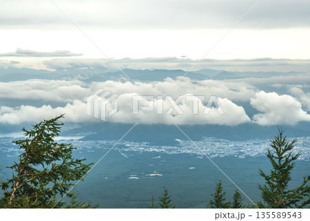 富士山五合目付近から雲海越しに望む富士河口湖町周辺の街並みと遠方に連なる山々の景観 135589543