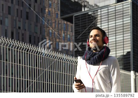Caucasian man listening to music with smartphone outdoors Caucasian man listening to music with smartphone outdoors 135589792