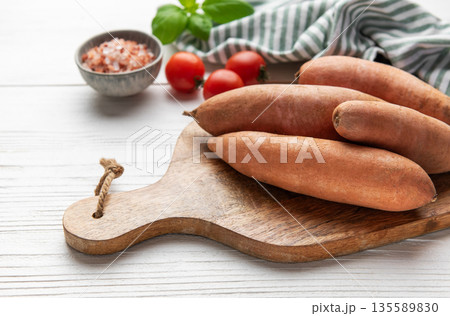 Sweet potatoes on cutting board with tomatoes and basil 135589830