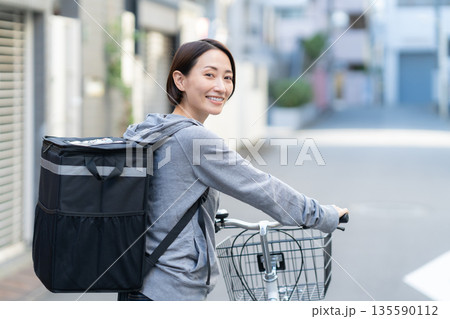 自転車でフードデリバリーをする配達員の女性 135590112