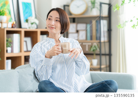 リビングのソファでくつろぐミドルの女性 リビングのソファでくつろぐミドルの女性 135590135