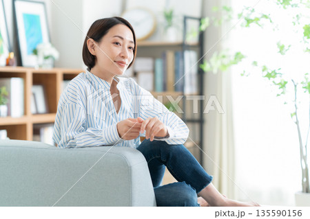 リビングのソファでくつろぐミドルの女性 リビングのソファでくつろぐミドルの女性 135590156