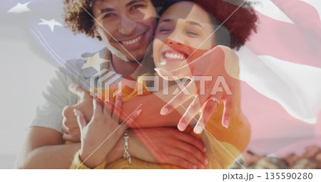 Hugging couple showcasing engagement ring on rocky shoreline at sunset, with flag overlay Hugging couple showcasing engagement ring on rocky shoreline at sunset, with flag overlay 135590280