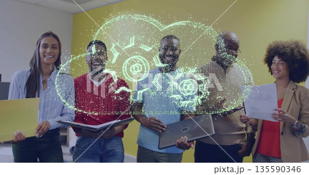 Standing colleagues holding laptop and documents in office with neon green cloud and gear overlay 135590346