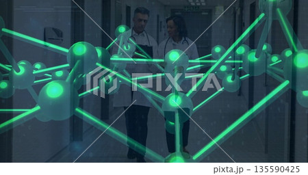 Walking senior doctor and female doctor discussing data in clinic hall with tablets, green network Walking senior doctor and female doctor discussing data in clinic hall with tablets, green network 135590425