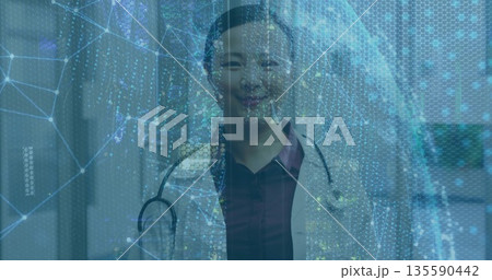 Standing Chinese doctor donning white coat in hospital corridor, stethoscope and digital overlay Standing Chinese doctor donning white coat in hospital corridor, stethoscope and digital overlay 135590442